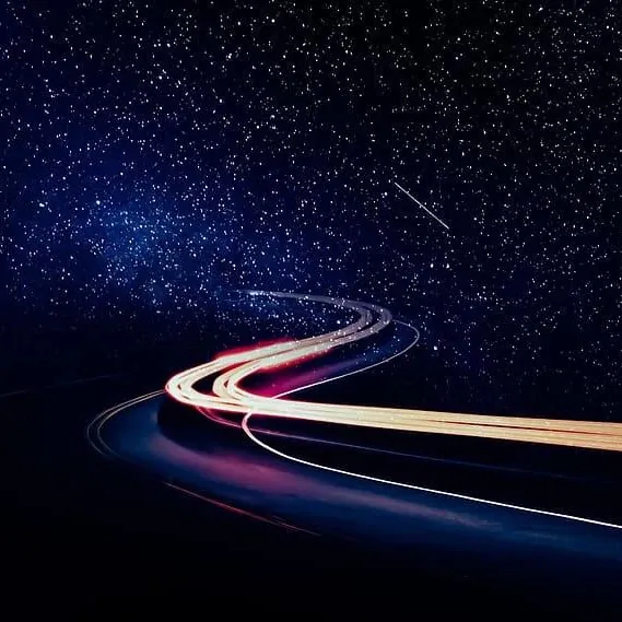 Light trails curving through a starry night sky